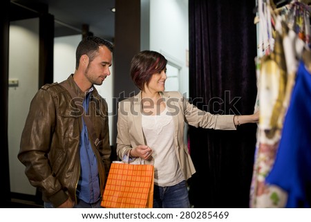 Woman smiling and looking clothes and man is boring because he prefer be in other place like a bar