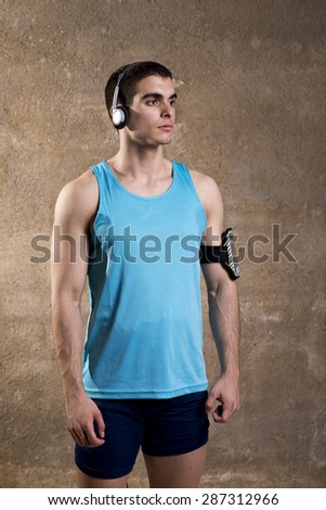 Runner posing in studio shot with head phones and phone bracelet gear