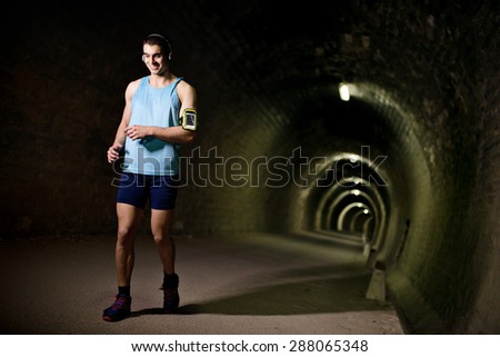 Young runner training inside a tunnel with ambient light