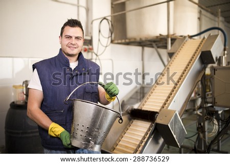 Worker posing near to sieve factory machine with ambient light