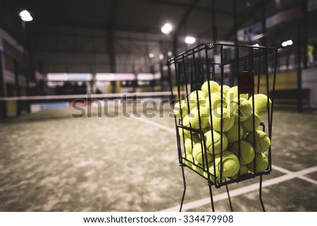Paddle tennis basket in court with balls.