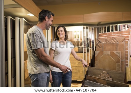 Happy couple pointing at ceramic tile for bathroom floor in store
