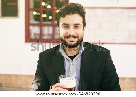 Bearded man drinking beer with suit in outdoors bar terrace