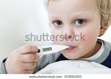 Portrait of a young child with a thermometer in his mouth measuring his fever
