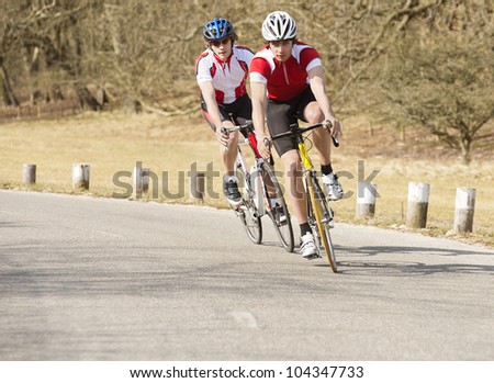 Active male bike riders riding cycles on a country road