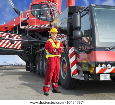 Crane driver, posing next to the huge mobile crane he\'s operating