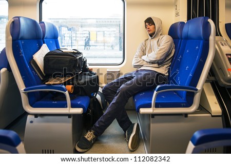 Young Man Sleeping In Train With Luggage