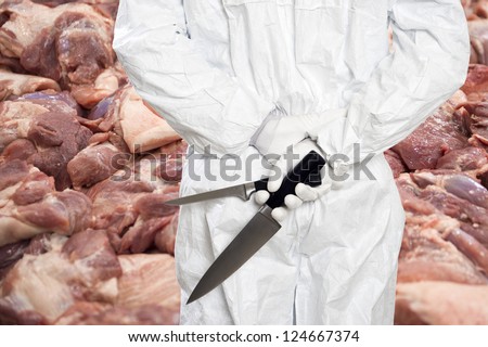 Butcher standing in front of a large stack of raw meat (pork chops), with his back to the camera, holding a large butcher\'s knife and a filleting knife, his work cut out for him