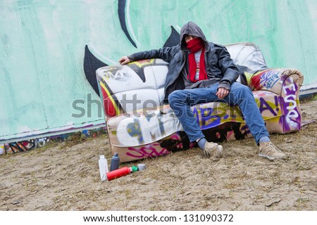 Graffiti artist sitting on a couch in a urban back street location