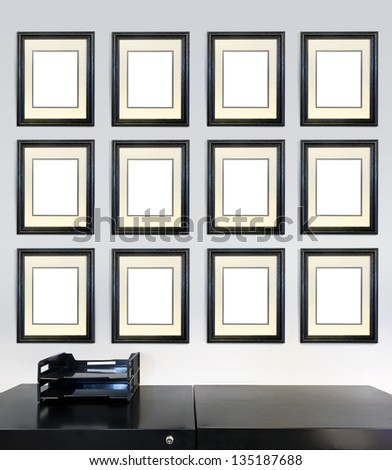 Twelve framed award certificates for employee of the month images on a wall in an office, in front of a file cabinet.