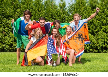 Portrait of cheerful young multiethnic athletes with various national flags celebrating in park