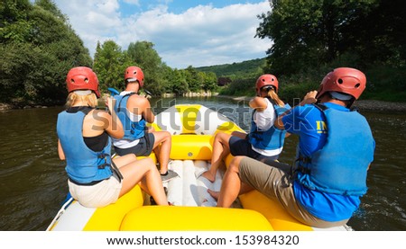 A group of friends in an inflatable raft moving down a river