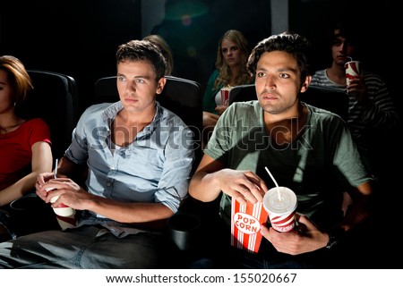 Two young men watching a movie in a cinema