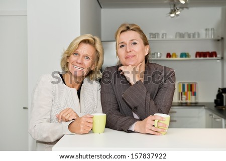 Portrait of female entrepreneurs with coffee mugs standing at counter in office