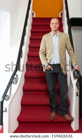 Portrait of a business man standing on steps, one hand on the railing, the other casually in his pocket
