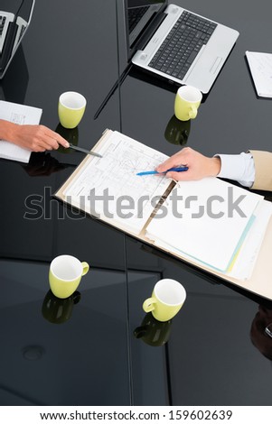 Hands of business people pointing at an industrial design technical drawing during a product design review meeting