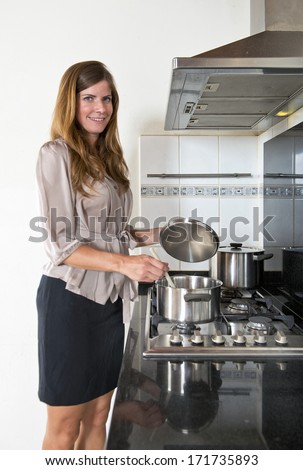 Young businesswoman cooking when she gets home after work. Life - work balance concept