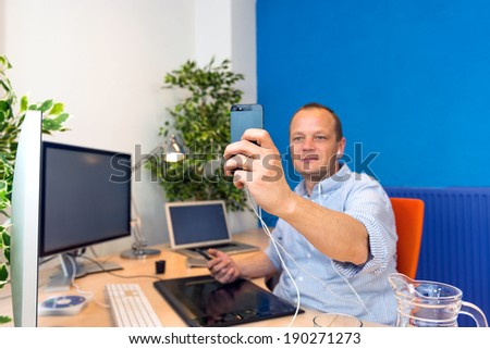 A business man taking a selfie in his clean and paperless office.