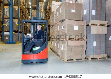 Reach truck forklift driving past an isle in a warehouse at speed. A panned image, with stock and cardboard boxes in the shelves of the storage racks. Conceptual image about internal logistics