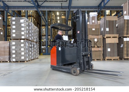 Reach truck driving around cartboard boxes in a warehouse.