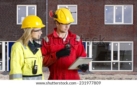 Foreman and real estate development manager going over an electronic checklist during the delivery and completion of a new housing development, constructed from prefab elements
