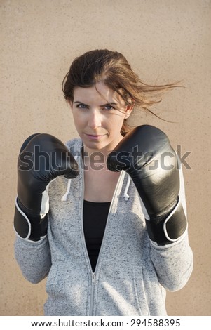 Portrait of confident young woman wearing boxing gloves outdoors