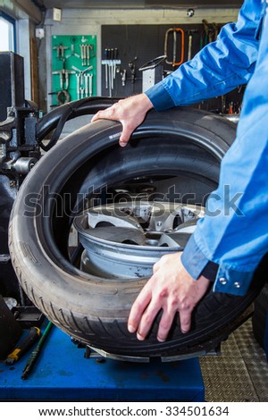 Mechanic mounting a tire on a light weight alloy rim in a garage