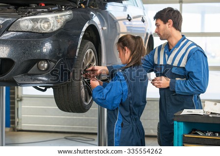 Mechanic teaching an intern the best practice. Learning on the job during a practical internship in a garage