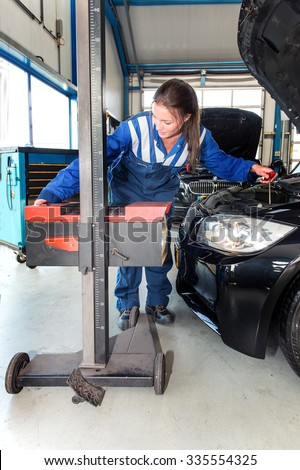 Mechanic, using an advanced measturing tool, to adjust the hight of a head light beam and high beam of a car as part of a MOT test