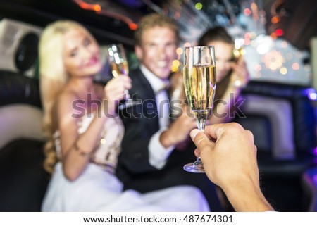 Party people toasting with glasses of champagne inside a limousine