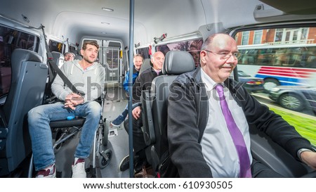 Group of people, traveling in a minivan with a disabled person in a wheel chair, surrounded by several others