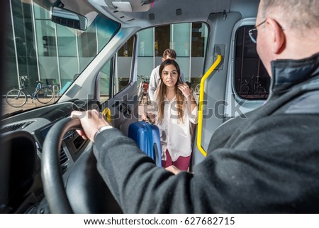 Professional male driver looking at passengers entering in van at airport