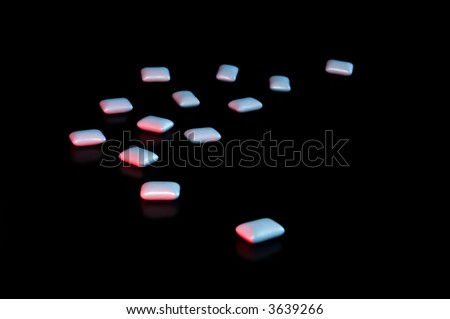 Blue Pills scattered over a black background, lit by a red and a blue light source