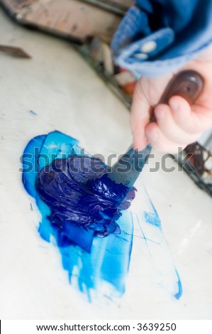 A hand using a filling knife to mix inks for the offset printing process