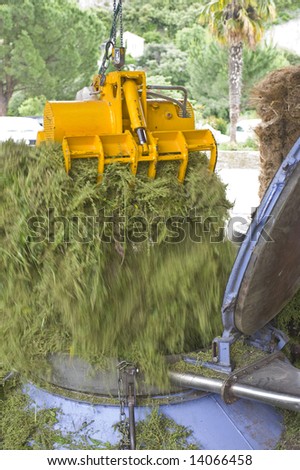 An overhead crane releasing herbs into an industrial pressure cooker, used in the distillery process to produce natural herbal essences
