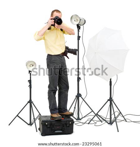 A professional photographer standing on a flight case to get a higher angle in a studio, surrounded by three strobes