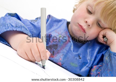 Sad looking child making a drawing with a felt-pen. Focus on the felt tip pan and hand
