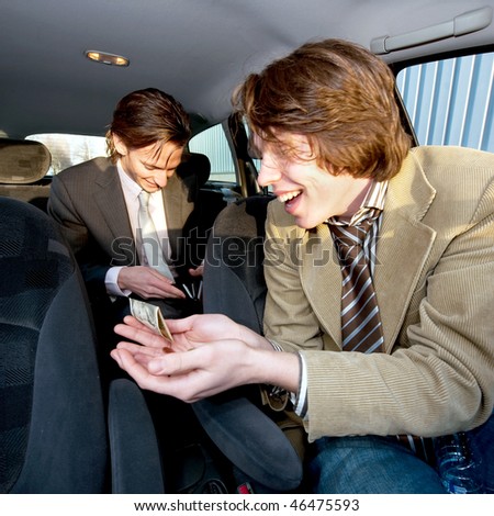 A customer in the backseat giving a tip to the cabby after having reached the destination