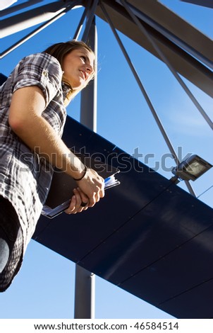 Young engineering student, holding her notes on a bridge on a sunny day