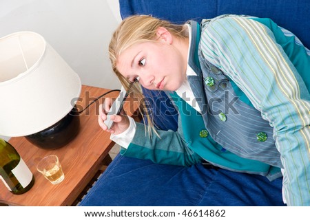 Woman, slouched on a couch, looking at the glass of white wine on the side table next to her