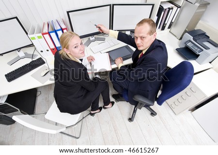 Two colleagues cooperating behind a dual flat screen monitor
