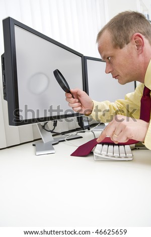 Businessman seriously analyzing data on a computer monitor using a magnifying glass, with his left index finger hovering above the escape key to interrupt the process.