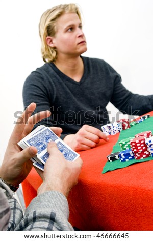 A card player shuffling cards during a poker game with one of his competitors in the background - Selective focus on the hands