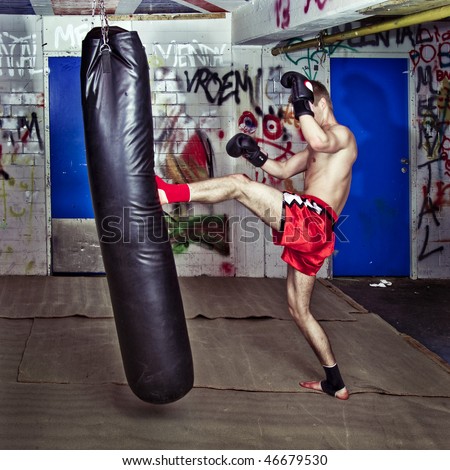 Muay Thai fighter giving a forceful forward kick during a practise round with a boxing bag