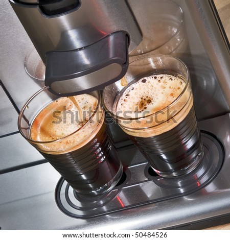 Pad coffee machine seen from above, brewing two glass cups of fresh, creamy coffee