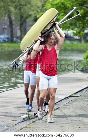 A rowing team carrying their boat to the boat house after a race