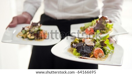 Waiter, carrying three plates with a rich salad