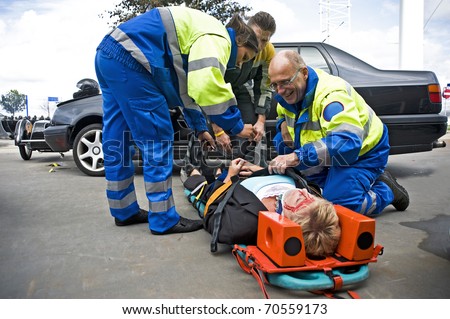 A team of emergency medical services at work, straping an injured driver to a stretcher