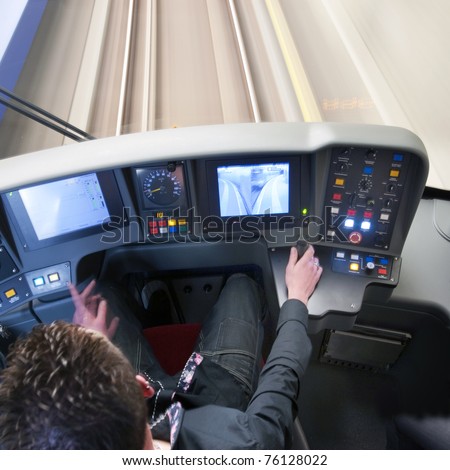 Train driver behind the dashboard controls of his carriage in the confined space of the cockpit