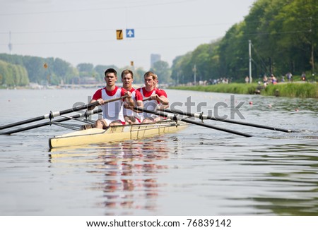Coxed four rowing team paddling backwards to the start, with concentrated looks in their eyes, in anticipation of the race ahead